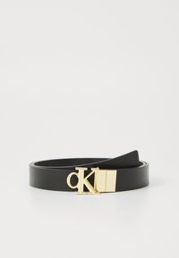 Svart lærbelte med gullspenne som har bokstavene "CK." Glatt tekstur, slank design og en klassisk rektangulær spenneform.