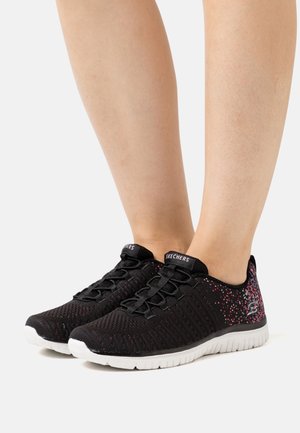 Chaussures de sport noires avec une tige en maille texturée, ornées de speckles roses, une semelle blanche et des lacets élastiques. Logo de la marque visible sur la languette.