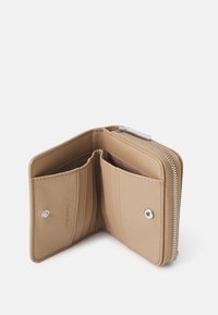 Cartera de cuero beige con cierre de cremallera, que cuenta con dos ranuras para tarjetas y una impresión de logotipo. Textura suave con acentos cosidos y una cremallera plateada.