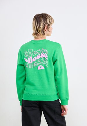 Zöld kapucnis pulóver, amelynek hátán nagy rózsaszín és fehér "ellesse" logó található. Kerek nyakú, bordázott mandzsettákkal és hem, puha tapintású, laza szabású.