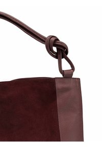 Sac à main bourgogne en suède texturé avec des accents en cuir lisse. Dispose d'une bandoulière en cuir nouée pour un détail supplémentaire.