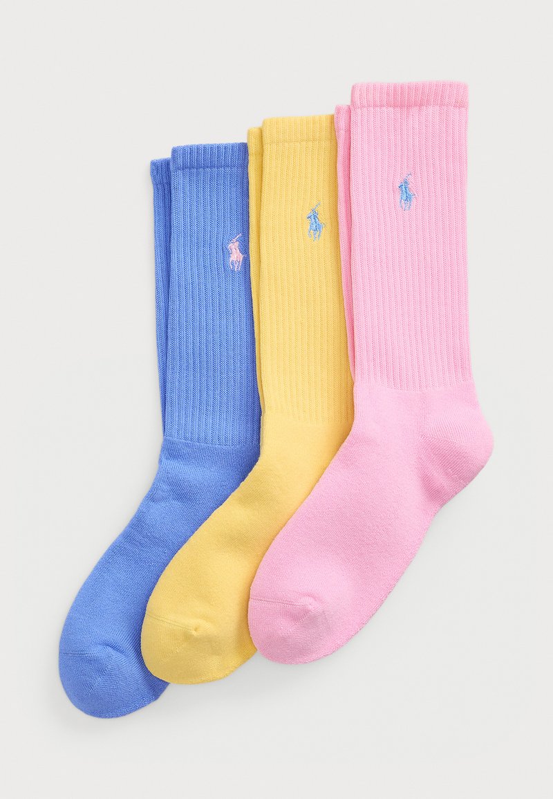 Τρία ζευγάρια ριγέ κάλτσες: ανοιχτό μπλε, κίτρινο και ροζ. Κάθε ζευγάρι διαθέτει ένα μικρό κεντημένο λογότυπο σε αντίθεση χρωμάτων. Μαλακό, μείγμα βαμβακιού.