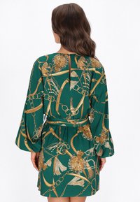 Zöld ruha arany lánccal és virágmintákkal, harang alakú ujjak, deréköv és kulcslyuk-hát részlet, könnyű anyagból készült.