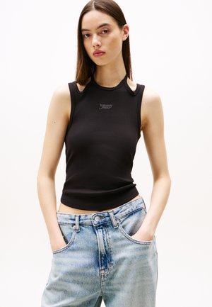 Must mustriba tank top avatud õlavarre detailidega ja väikese "Tommy Jeans" logoga. Koos helesiniste kõrge vöökohaga teksadega.