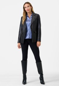 Black leather blazer over a blue button-up shirt, paired with black leggings and knee-high black heeled boots. Smooth texture, tailored fit.