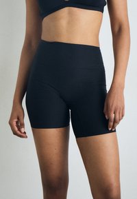 Black high-waisted bike shorts with a smooth texture, fitted design, and mid-thigh length. Features minimal stitching details.