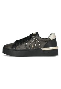 Sneaker nera con tomaia texturizzata, dotata di dettagli in oro e argento, borchie decorative e una suola nera spessa. Branding sul lato.