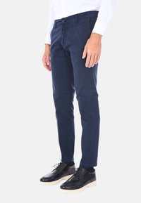 Chinos blu navy con vestibilità dritta, realizzati in tessuto di cotone, dotati di chiusura a bottone singolo e tasche laterali, abbinati a scarpe in pelle nera.