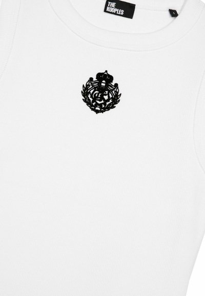 Maglietta senza maniche bianca a costine con logo ricamato nero e design di alloro sul petto. L'etichetta reca la scritta "THE KOOPLES". Texture liscia.