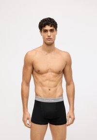 Czarne bawełniane bokserki z jasnoszarym elastycznym paskiem w talii z logo "Calvin Klein", dopasowany krój i gładka faktura.