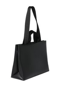 Zwarte draagtas van mat leer, voorzien van twee handvatten en een gestructureerde vorm met een vlakke bodem. Subtiele gegraveerde merknaam op de riemen.