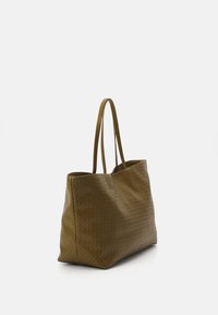 Woven tote bag w kolorze oliwkowym, wykonana z teksturowanego materiału. Posiada dwie długie rączki oraz przestronny, otwarty design.