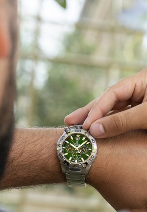 Orologio da polso in acciaio inossidabile con quadrante verde, accenti argento e funzioni cronografo. L'orologio presenta grandi indicatori delle ore luminosi e un cinturino in metallo.
