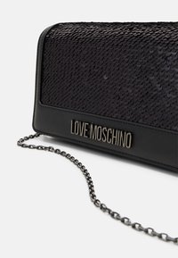 Black sequin clutch bag with a chain strap and a logo plaque. The bag features a textured, shiny surface and smooth edges.