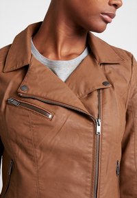 Bruine leren motorjack met ritssluitingen, drukknoopsluitingen en een gestructureerde kraag, met een gladde, gestructureerde afwerking.