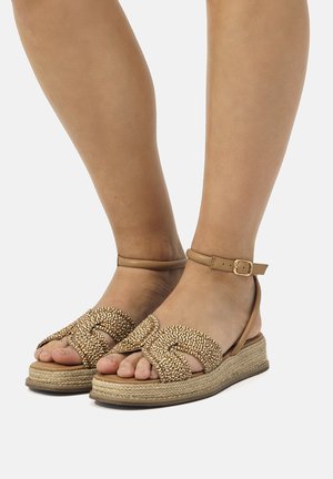 Sandali espadrilles intrecciati marroni con design incrociato e cinturino alla caviglia, caratterizzati da una superficie testurizzata e una suola a zeppa avvolta in juta.