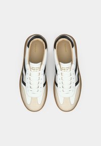Paire de baskets GANT blanches et beige avec des accents noirs et des semelles en gomme, vues de dessus sur un fond uni.