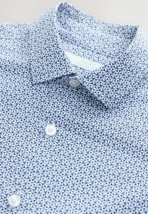 Camicetta azzurro chiaro con un motivo geometrico in blu scuro, collerino button-down e bottoni bianchi, realizzata in un tessuto liscio.