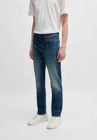 Denim farkut keskisinisessä sävyssä, jossa on hieman haalistunut viimeistely. Suora lahjetyyli viidellä taskulla ja vetoketjclosure. Yhdistettynä valkoisiin lenkkareihin.