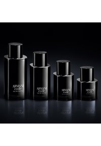 Fire svarte Armani Code Eau de Parfum-flasker i synkende størrelse på en reflekterende mørk overflate med en svart bakgrunn.