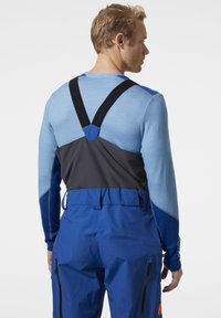 Modrá technická bunda s černými a šedými akcenty, vybavená nastavitelnými popruhy, těsným střihem a texturovanou tkaninou pro zvýšené pohodlí.