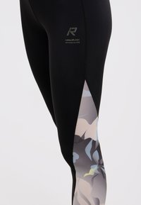 Leggings sportivi neri con un motivo floreale in grigio, blu e beige sul lato inferiore, dotati di un logo in rilievo sulla coscia.