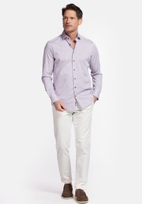 Chemise habillée à motifs violet clair avec des boutons noirs, associée à un pantalon blanc et des chaussures marron. Conçue pour un ajustement sur mesure.