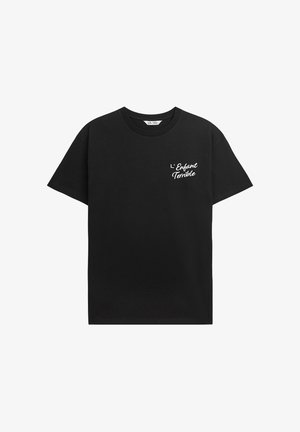 Schwarzes Baumwoll-T-Shirt mit kurzen Ärmeln, Rundhalsausschnitt und weißem Drucktext "L'Enfant Terrible" auf der oberen linken Seite.