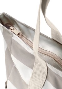 Beige és fehér csíkos vászontáska, bézs cipzárral és erős szőtt fogantyúkkal, közelről, fehér háttér előtt.