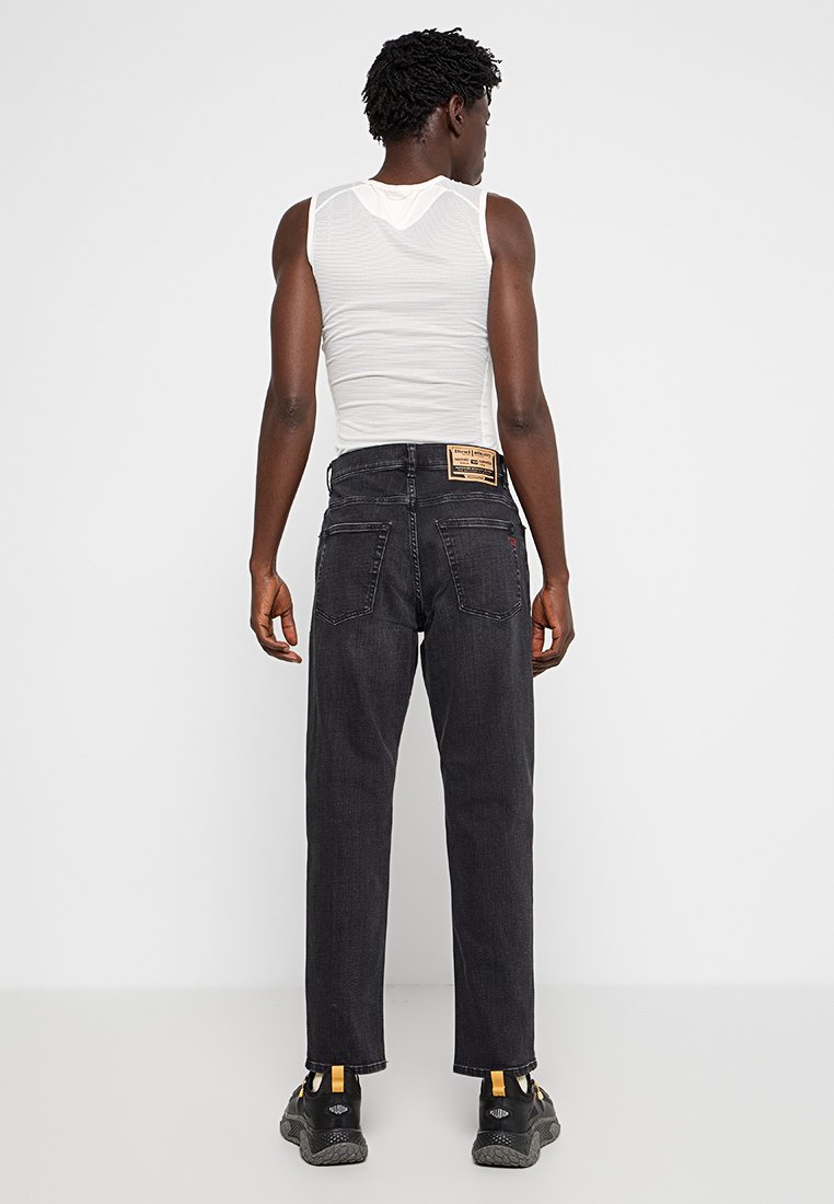 Jean en denim noir avec une coupe droite, doté de deux poches arrière, d'une étiquette en cuir de marque et de détails de couture subtils.