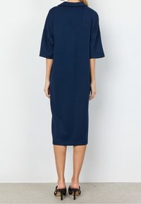Navy blue midi dress with short sleeves and a collar, featuring a straight cut and soft texture, paired with black heeled sandals.