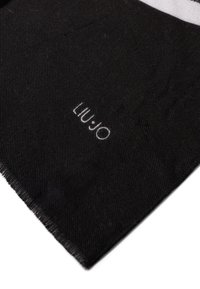 Pezzetto di tessuto nero con una fine trama a righe, bordo sfrangiato e logo bianco ricamato "LIU·JO" vicino all'angolo su uno sfondo bianco.