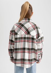 Oversized flannelskjorte i hvid, pink og grøn ternet mønster. Har lange ærmer, krave og rundet kant.