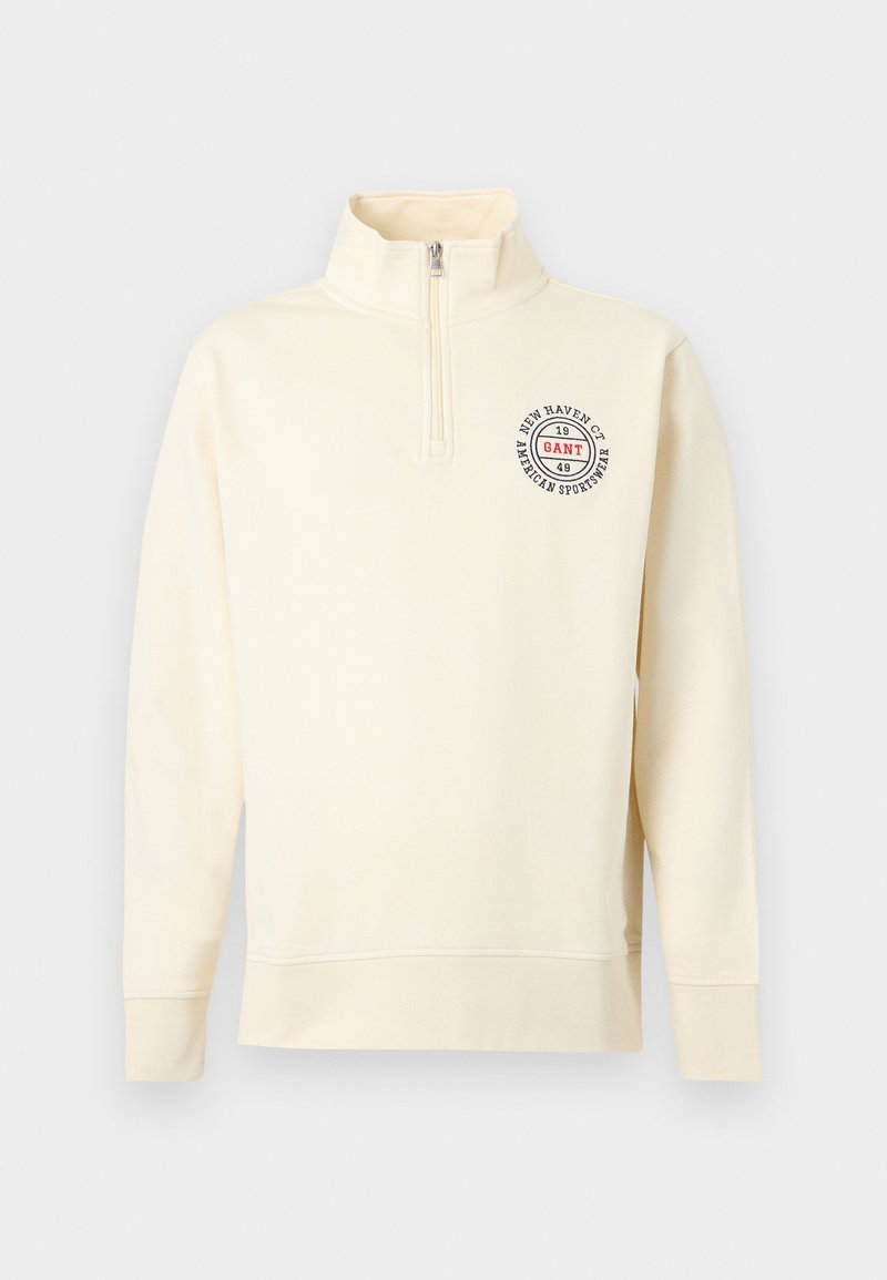 Felpa color crema con collo a mezza zip e logo tondo sul petto a sinistra. Realizzata in tessuto morbido con polsini a costine.