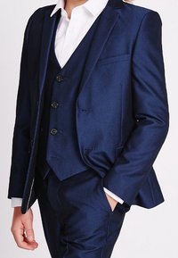 Granatowy, trzyczęściowy garnitur z satynowym wykończeniem, stójką w kształcie litery V oraz jednorzędową marynarką z czterema guzikami i dopasowanym krojem.