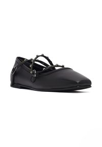Scarpa piatta nera con punta appuntita, realizzata in pelle liscia. Presenta cinturini incrociati con accenti metallici e una suola morbida e flessibile.