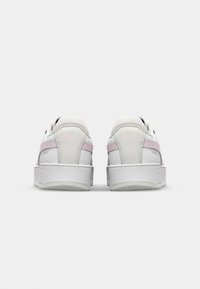 White and pink sneakers with a smooth leather upper, padded collar, and a textured rubber sole, featuring a subtle logo on the heel.