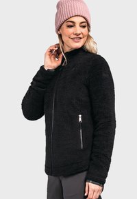 Schwarze Fleecejacke mit einem Reißverschluss vorne, Seitentaschen und hohem Kragen. Getragen mit einer rosa Strickmütze. Weicher Stoff, lässiges Design.