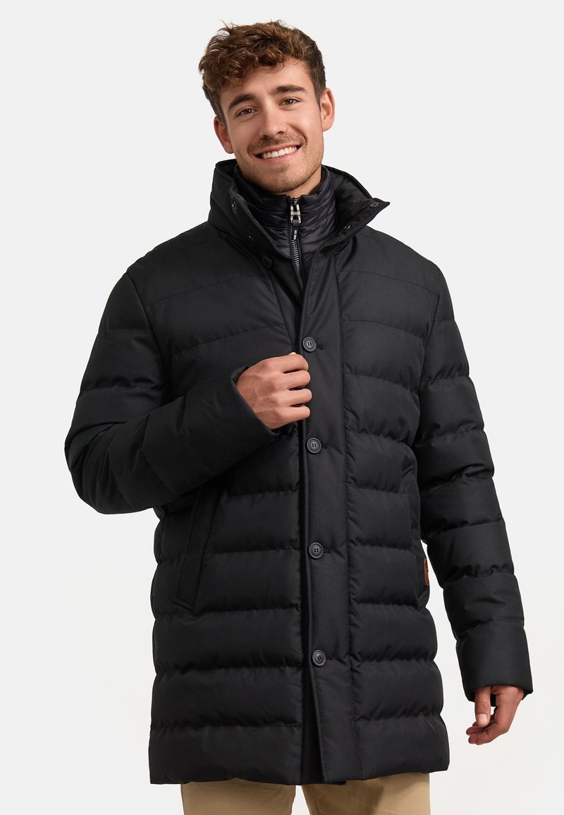 Zwarte pufferjas met een hoge kraag, horizontale quilting en knoopsluiting. Beschikt over een gladde textuur en elastische manchetten.