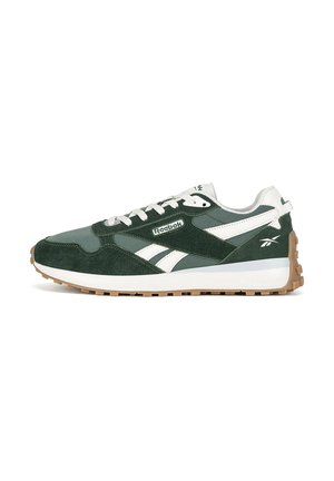 Zöld és fehér sportcipők velúr és hálós felsőrésszel, texturált gumitalppal és Reebok logóval az oldalukon.