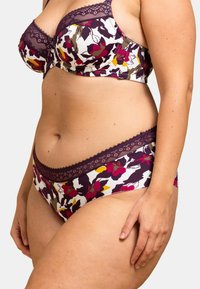 Ensemble soutien-gorge et culotte avec un motif floral en violet profond, rose et jaune sur fond blanc. Des bordures en dentelle ornent les pièces.
