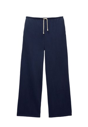 Pantalons larges bleu marine avec taille élastique et cordon blanc, posés à plat sur un fond blanc.