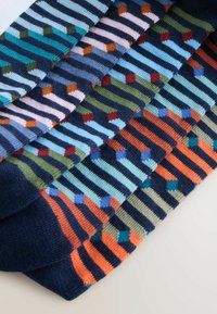 Gemischte Socken in verschiedenen Farben: dunkelblau, grün und orange mit Streifen und geometrischen Mustern aus kleinen Rauten und Rechtecken.