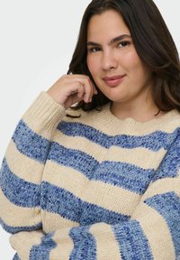 Gebreide trui met crème en blauwe strepen, voorzien van een ronde halslijn en textuurgaren. Blauwe draden zorgen voor een subtiele glans. Casual pasvorm.