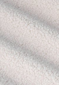 Tissu en polaire de couleur claire, avec une surface douce, texturée et duveteuse, présentant un motif bosselé uniforme sur toute la surface.