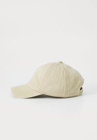 Beige pamutszövet baseball sapka; hatpaneles dizájn, ívelt napszemüveg és állítható pánt hátul. Panelenként különböző varrási részletek.