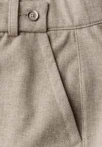 Béžová látka z vlněné směsi s texturovaným vzorem houndstooth, která má výrazný detail knoflíku a strukturované skladu.