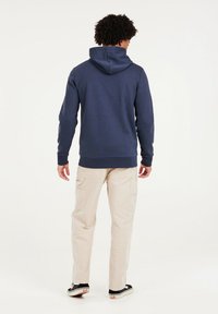 Navy blue hoodie with a relaxed fit and a kangaroo pocket, paired with light beige cargo pants featuring side pockets and cuffs.