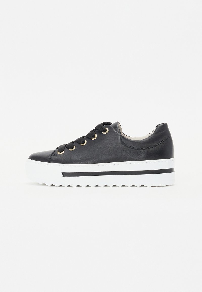 Sorte skinnesneakers med gullfargede øyer, hvit sikksakk såle og svart stripe på siden. Rund tå og flat hæl design.