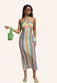 Bunt gestreiftes Halterkleid mit einem enganliegenden Oberteil und fließendem Rock. Enthält eine grüne gewebte Tasche und passende Accessoires.